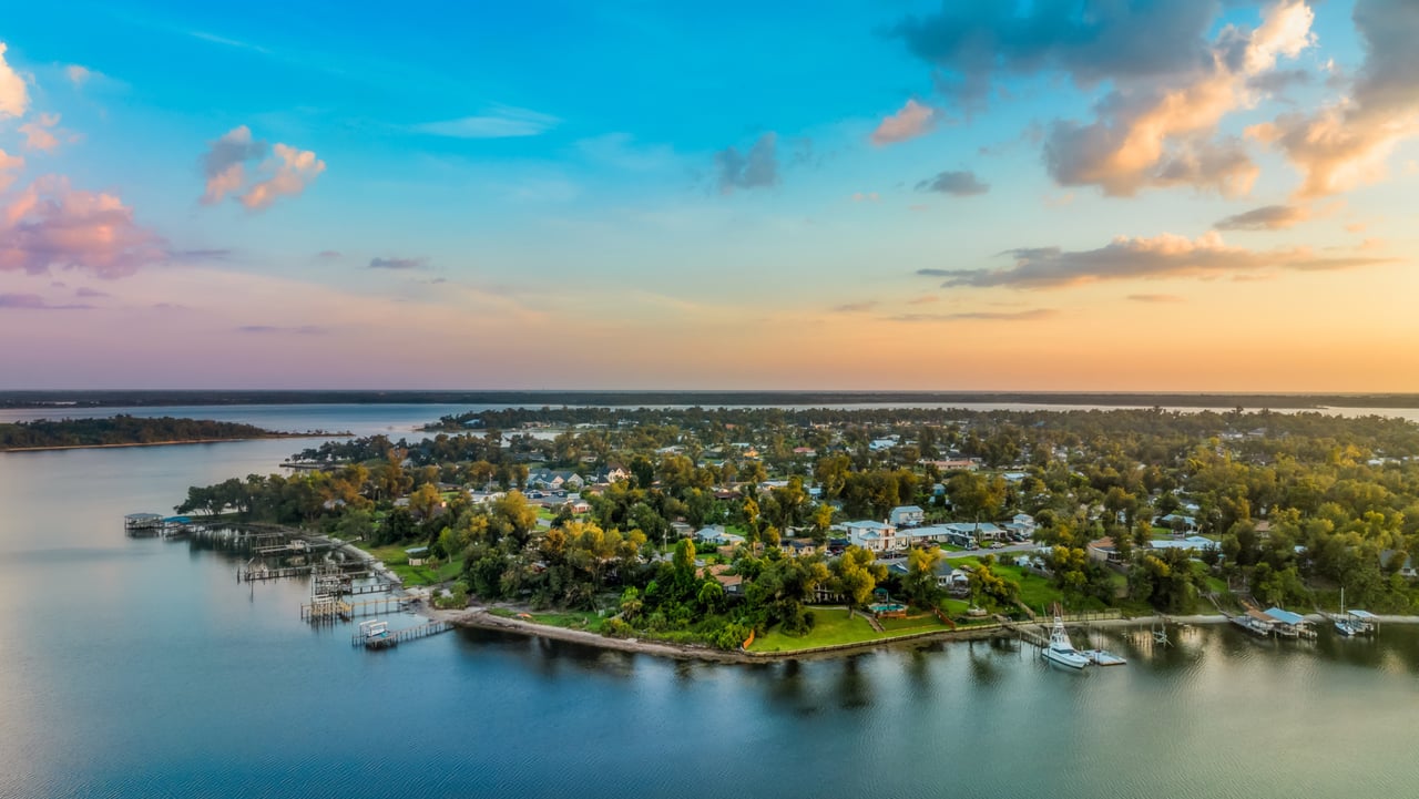 Aerial view of The Cove waterfront neighborhood at sunset, with homes, docks, and boats.