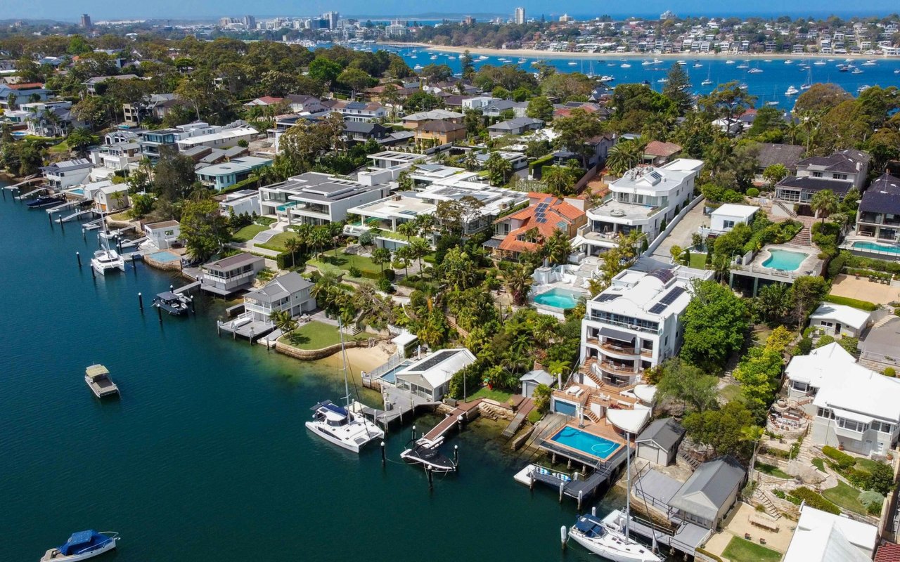 Aerial view of waterfront homes with private docks, boats, and pools along blue canals.