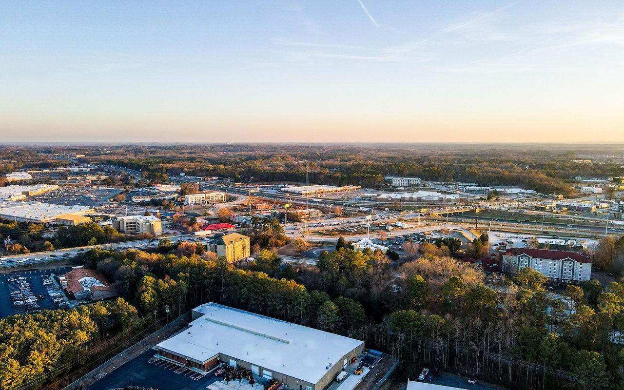 Aerial view of Conyers commercial buildings and roads amid autumn trees at golden hour.