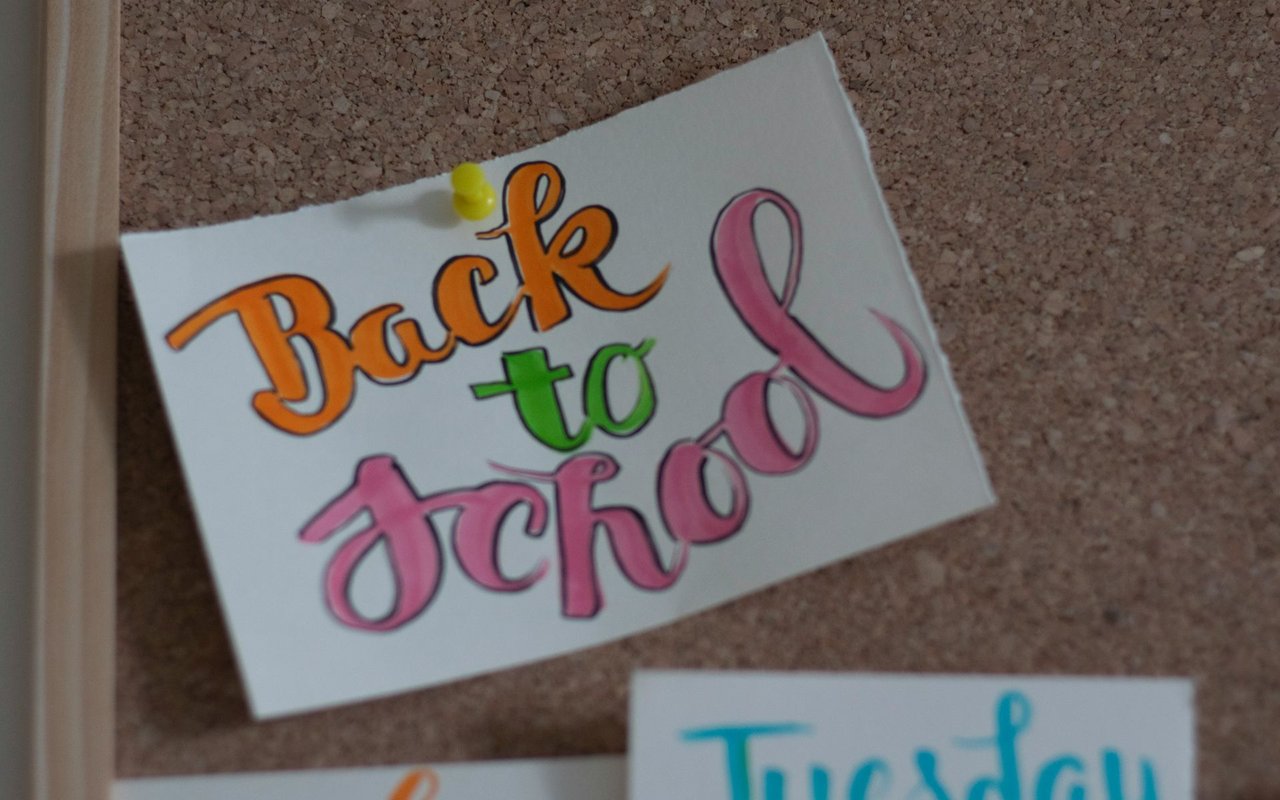 Handmade “Back to school” sign pinned to a corkboard with a yellow pushpin.