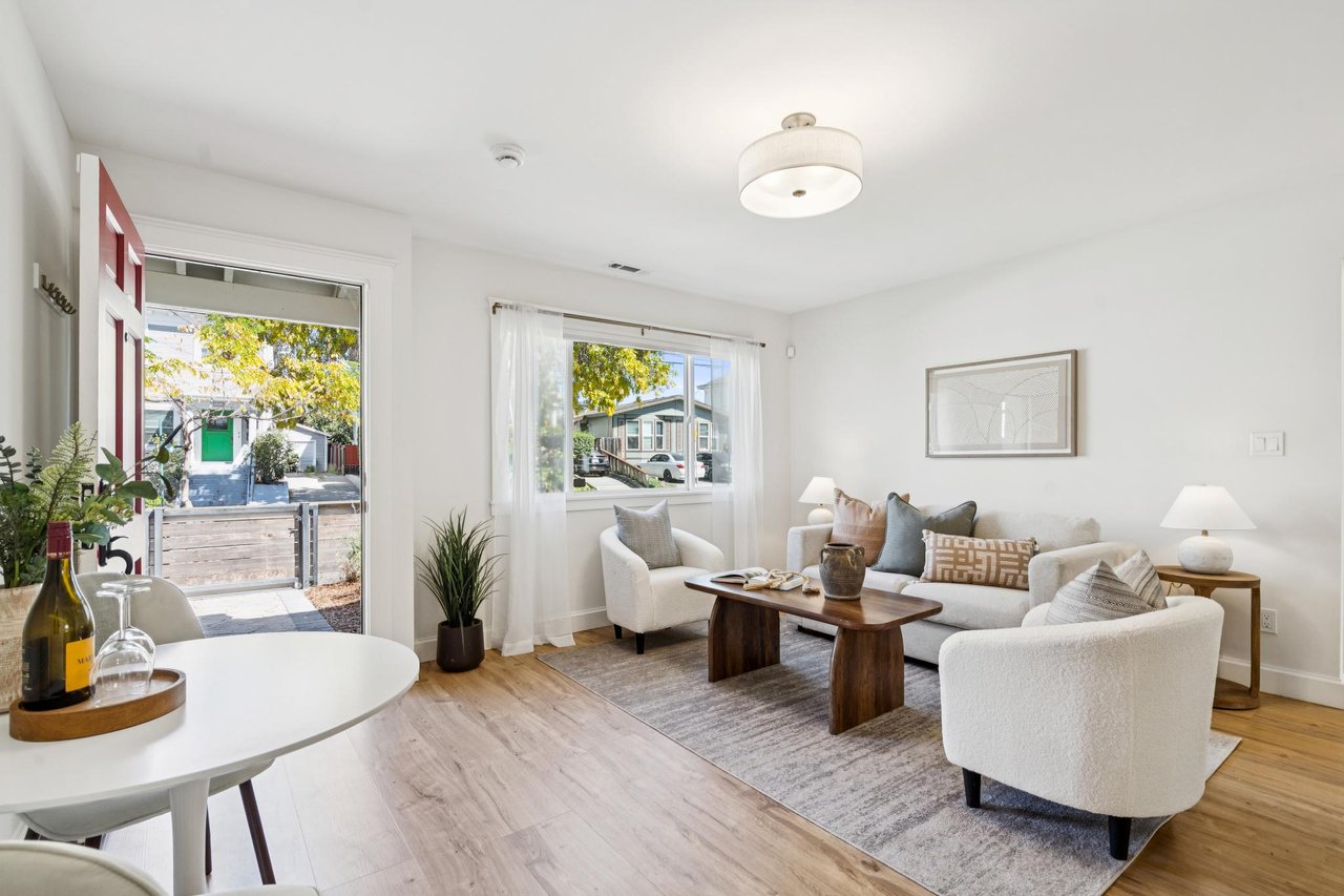Bright living room with white seating, a wooden coffee table, and an open red front door.
