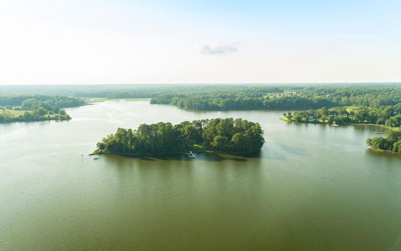 Aerial view of a waterway with wooded islands, a dock, and boats.