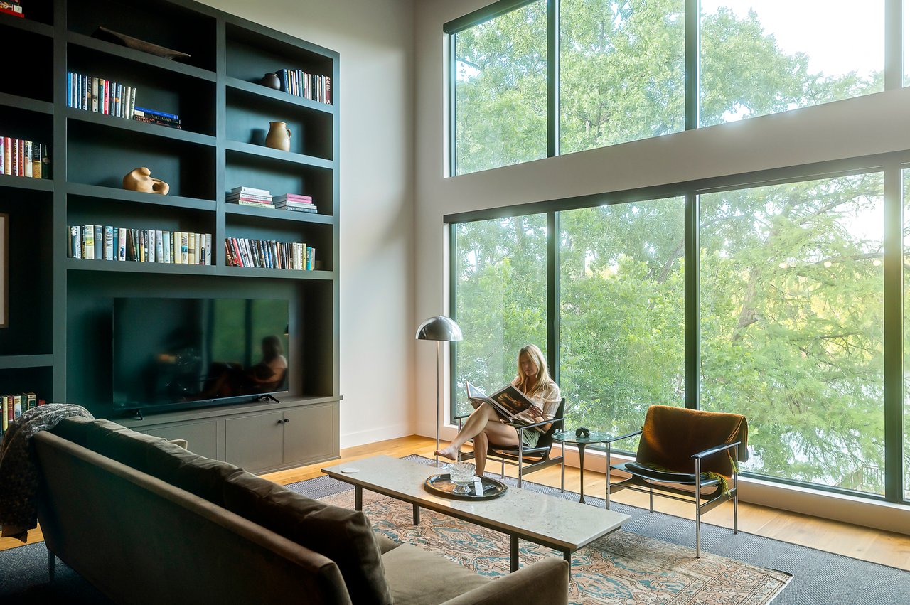 Living room with a wall of windows to Lake Austin and white oak floors, furnished by Liz MacPhail Interiors at 2403 Big Horn Drive, Austin.