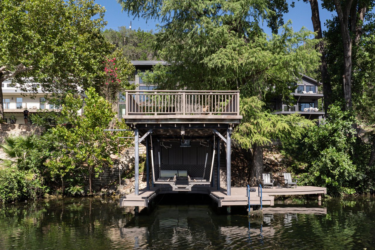 Grandfathered two-level boat dock viewed from the water beneath cypress trees on Lake Austin at 2403 Big Horn Drive, Austin.