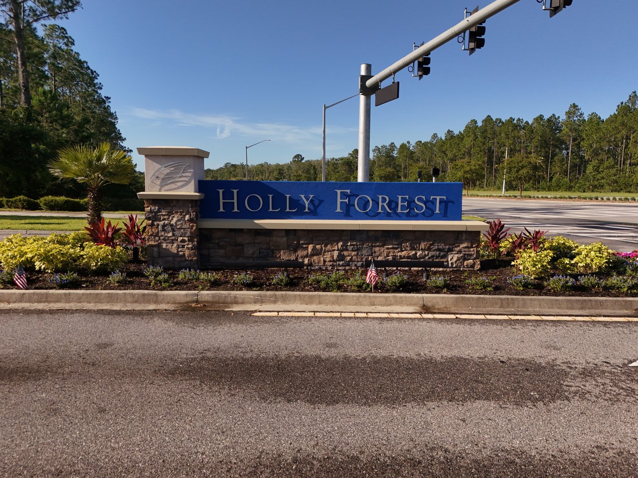 Holly Forest entrance sign with stone base and landscaped flower beds.