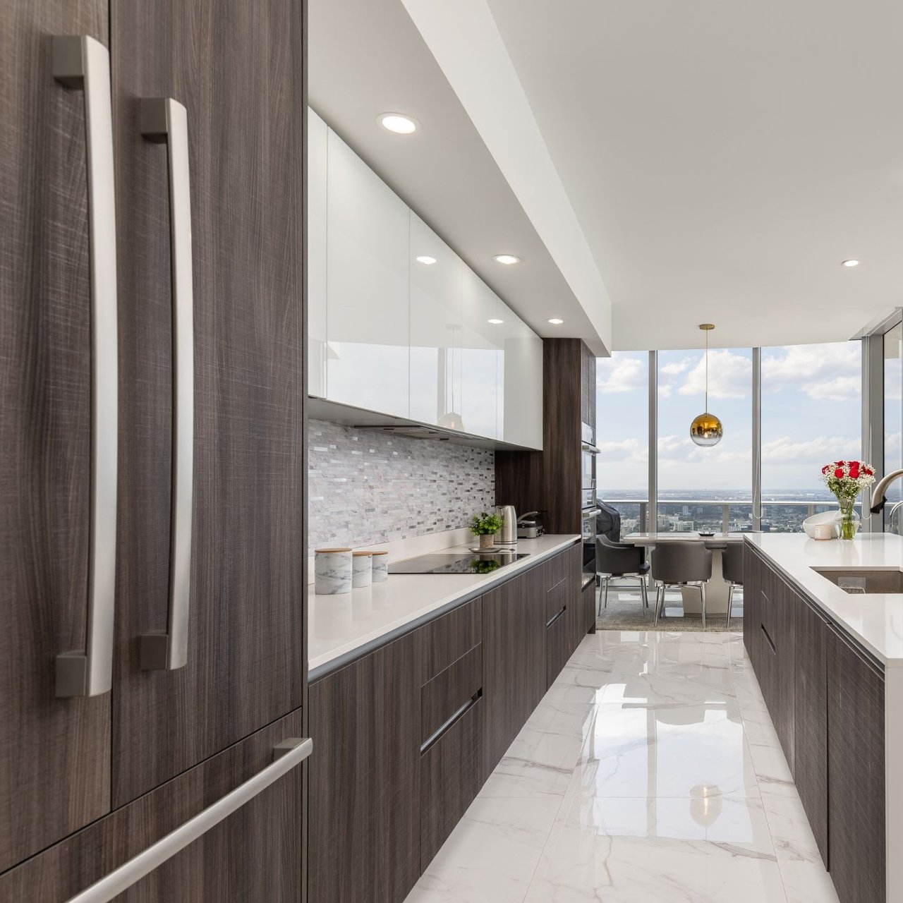 The kitchen features dark wood grain lower cabinets and white upper cabinets, with a white marble backsplash.