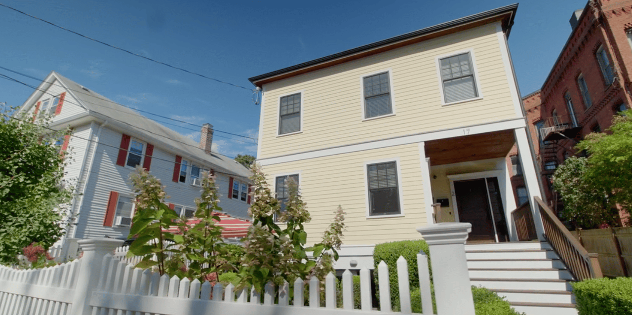 Pale yellow home at 17 Davis Avenue with a covered entrance, front steps, and white picket fence.
