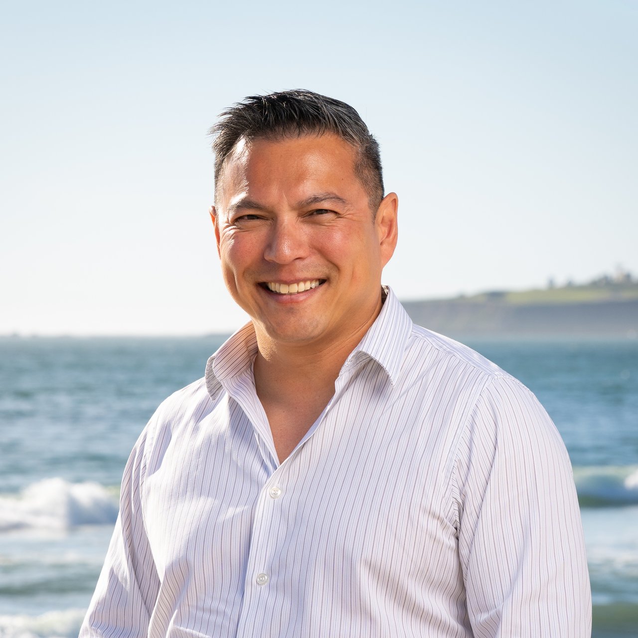 Colin Leow, Half Moon Bay real estate agent with Ocean Element Real Estate, standing on a Coastside beach with ocean views in San Mateo County