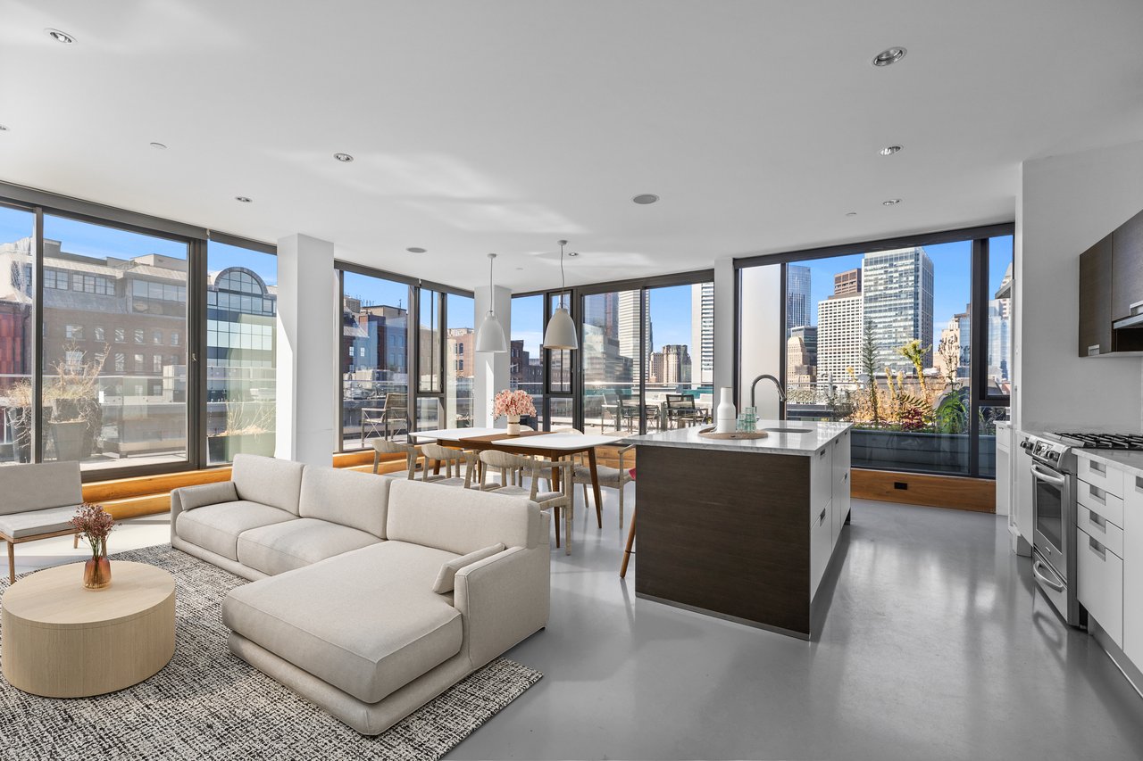 Open-plan living room and kitchen with a dark island, floor-to-ceiling windows, and Boston skyline views.
