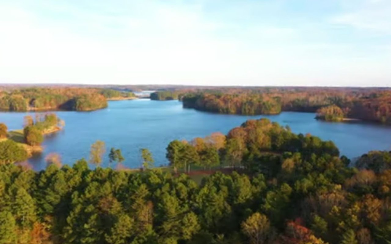Aerial view of a lake winding among autumn-colored wooded shores.