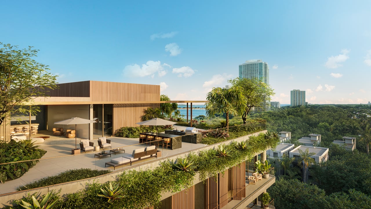 Rooftop lounge at Colette Residences with outdoor kitchen, seating areas, lush landscaping, and elevated views toward Biscayne Bay.