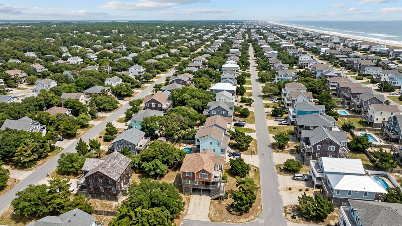 Aerial view of coastal homes and tree-lined streets beside the ocean.