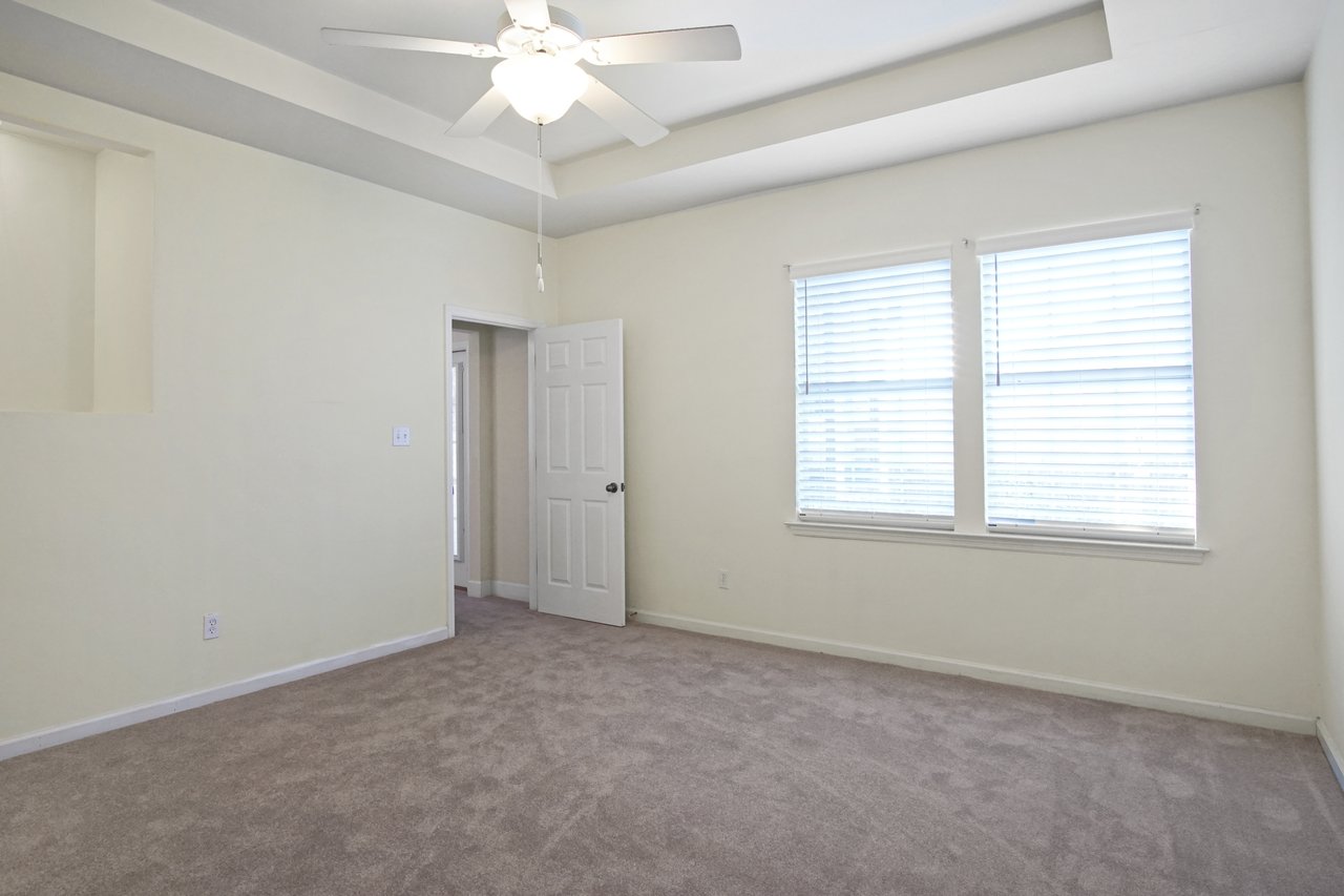 Bedroom at 5441 Hampton Hill Circle, Tallahassee, Florida 32311 with tray ceiling, ceiling fan, carpet flooring, and double windows.