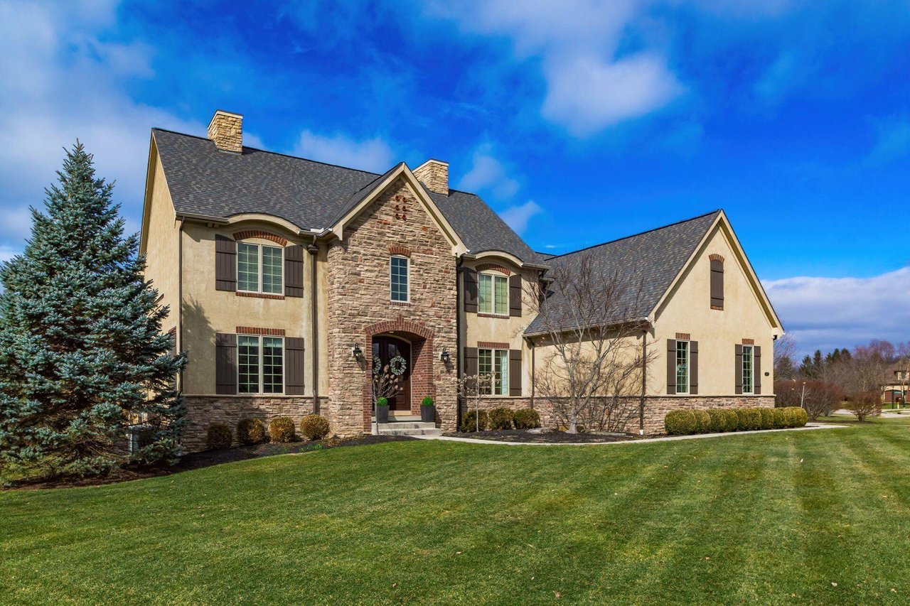 Luxury stone and stucco home in Powell, Ohio with arched entry, dual chimneys, and expansive lot — representative of the established Powell luxury market