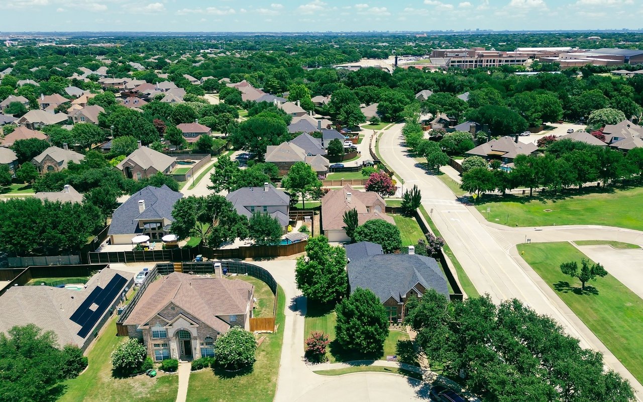 Aerial view of Coppell homes among mature trees and curving residential streets.