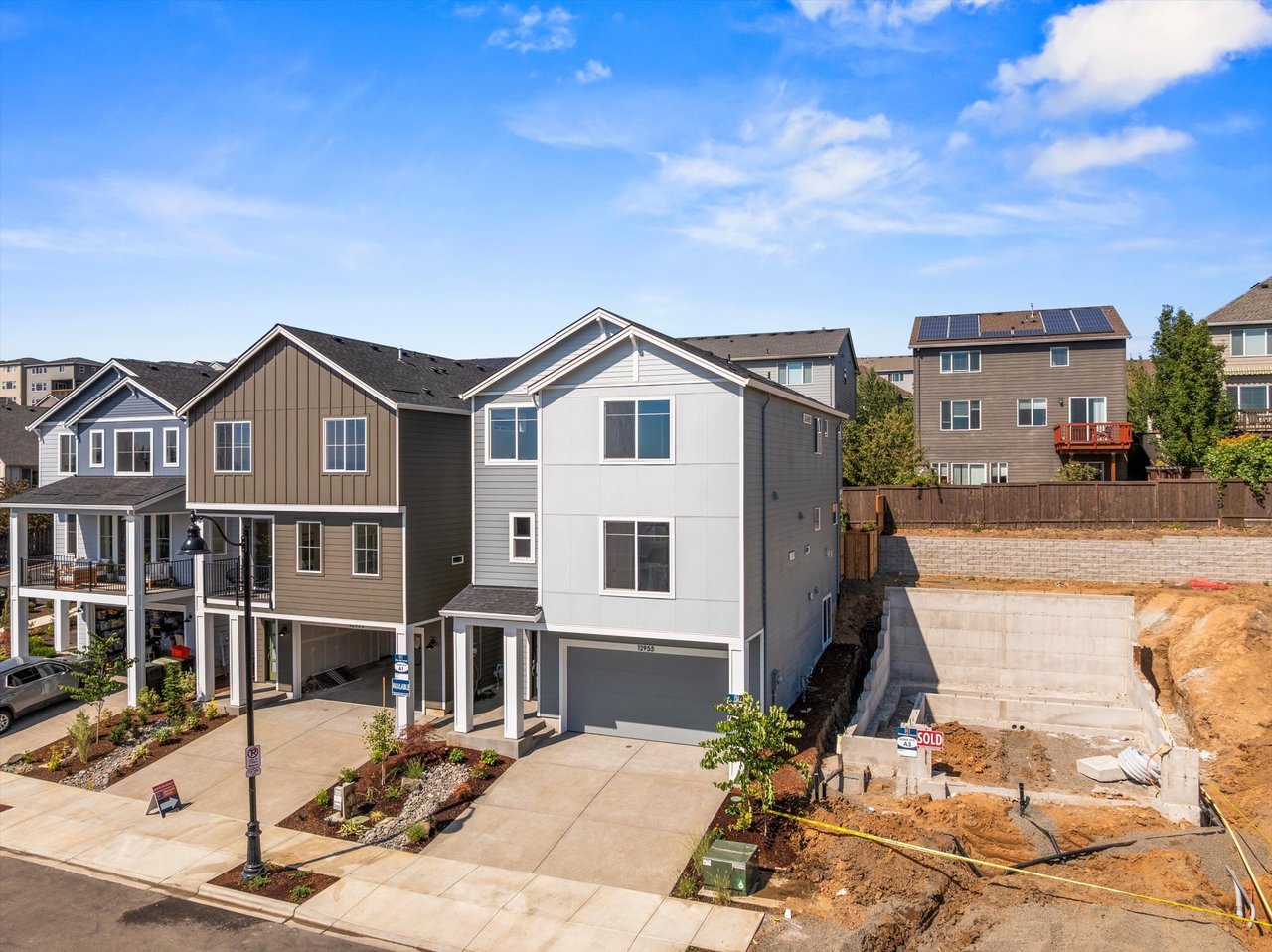 Front view of a modern, move-in ready home in Bethany, Oregon surrounded by trees — showcasing new construction with family-friendly curb appeal in fall 2025.