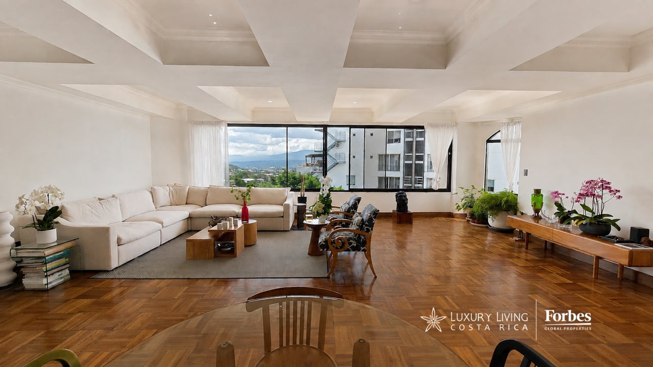 Condominium living room with parquet floors, a white sectional, and mountain views through large windows.