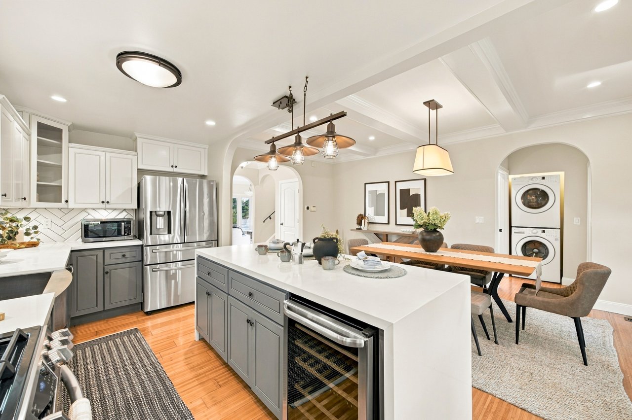Kitchen with a large white island, gray cabinets, stainless appliances, and an adjoining dining area.