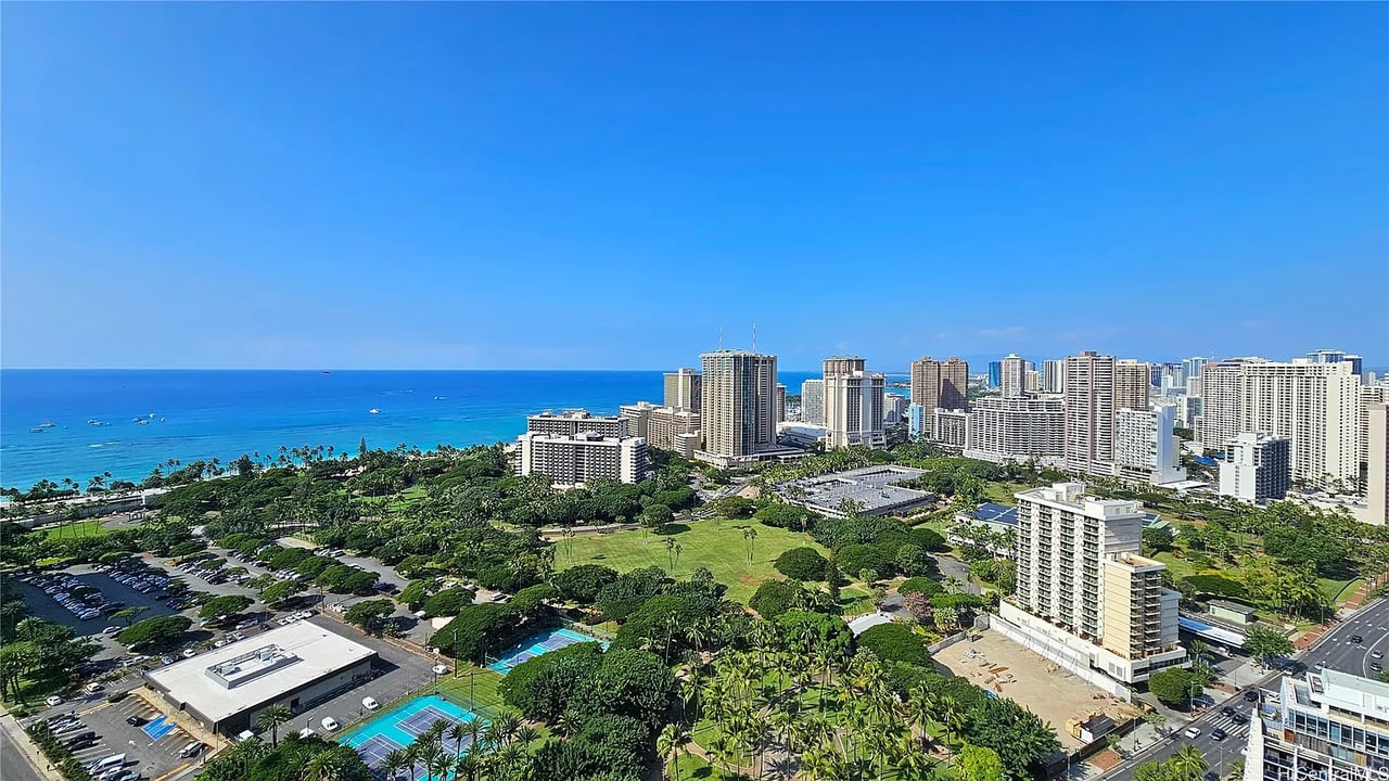 Panoramic Waikiki view with the Pacific Ocean, beachfront, Honolulu skyline, and green parkland.