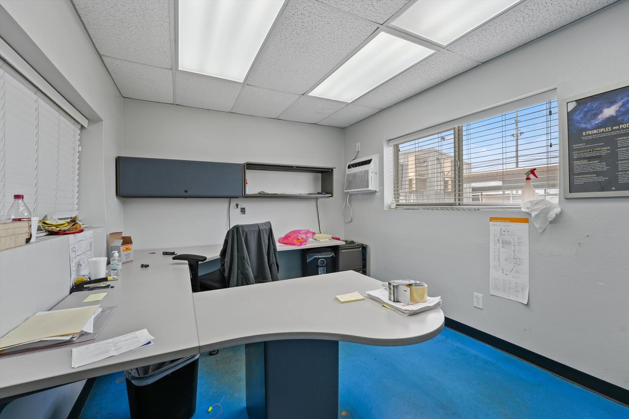 Office workspace with a curved reception desk, wall-mounted storage, and blue flooring.