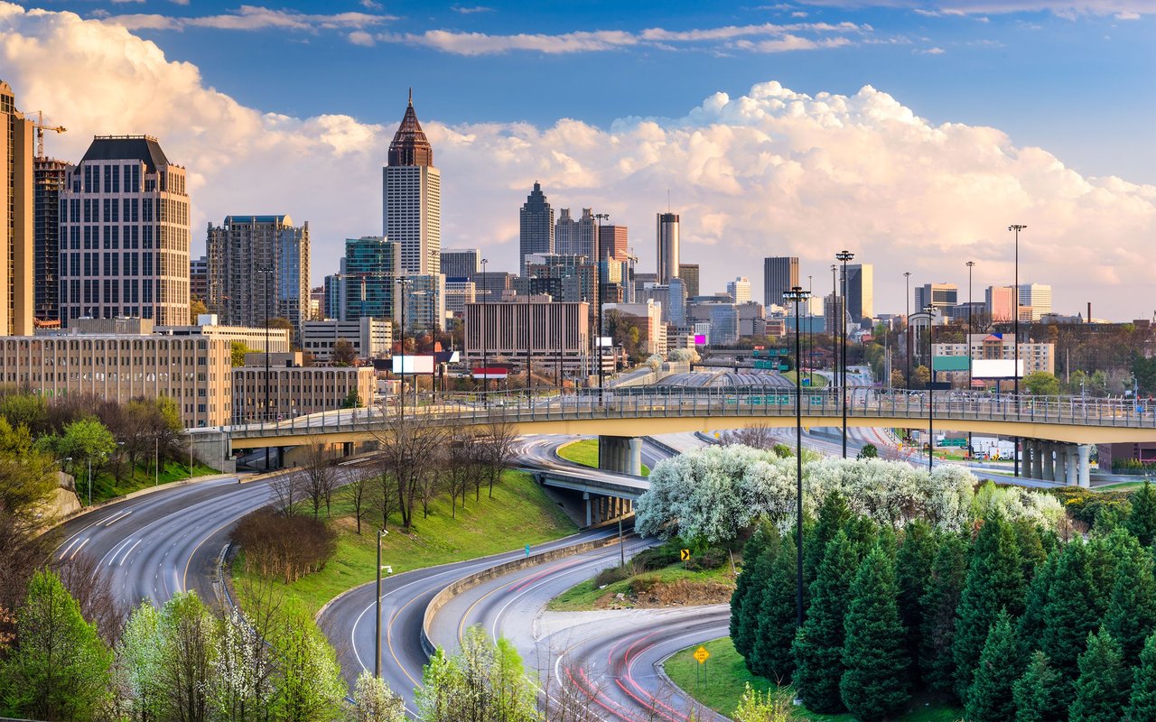 Atlanta skyline above curving highways and elevated bridges in warm evening light.