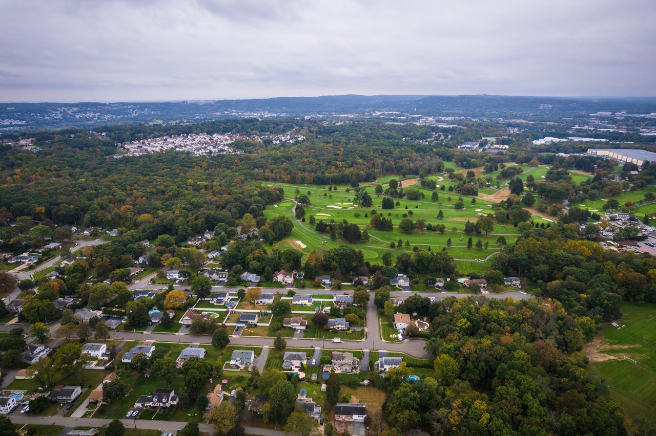 Aerial view of a suburban neighborhood and golf course amid autumn foliage.