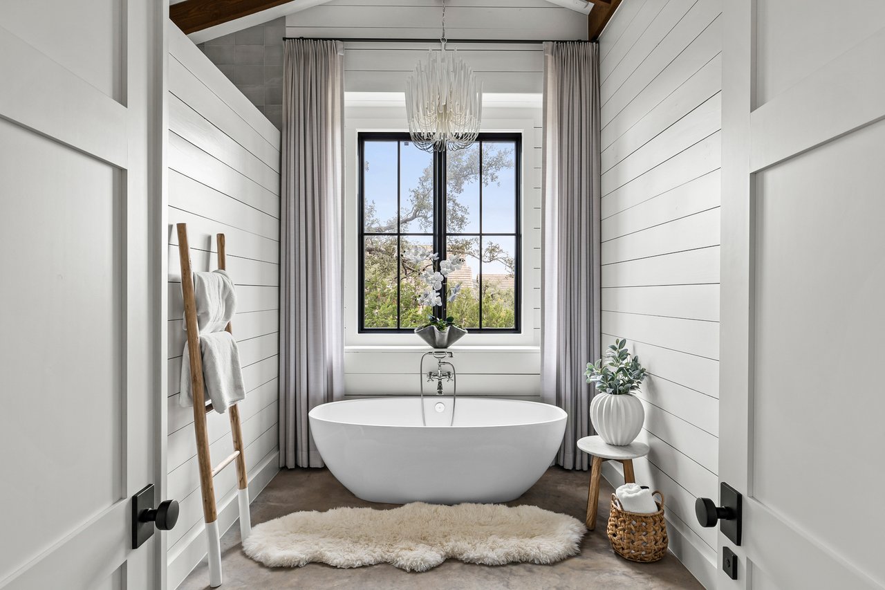 Bathroom with a freestanding soaking tub and shiplap walls in this Creek Road Ranch home in Dripping Springs, Texas.
