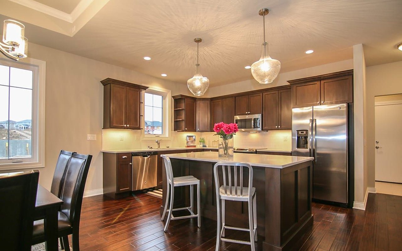 Kitchen with dark wood cabinets, stainless steel appliances, and a large island with pendant lights.