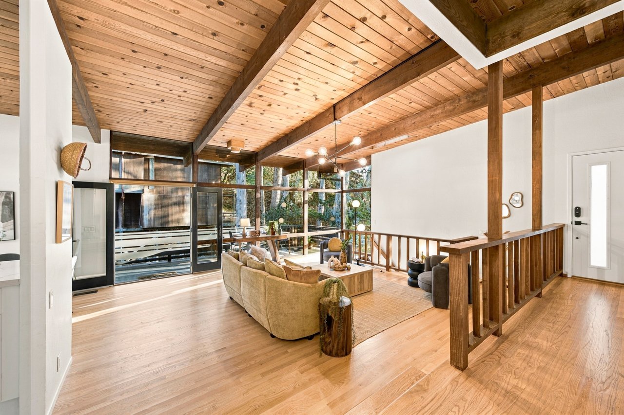 Living room with a vaulted wood ceiling, exposed beams, and floor-to-ceiling windows.