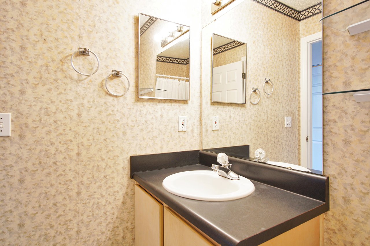 A clean bathroom featuring a modern sink and a large mirror reflecting the bright, well-lit space.