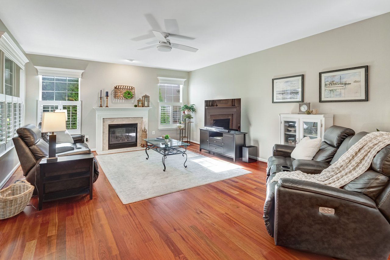 Living room with a fireplace, hardwood floors, and leather seating.