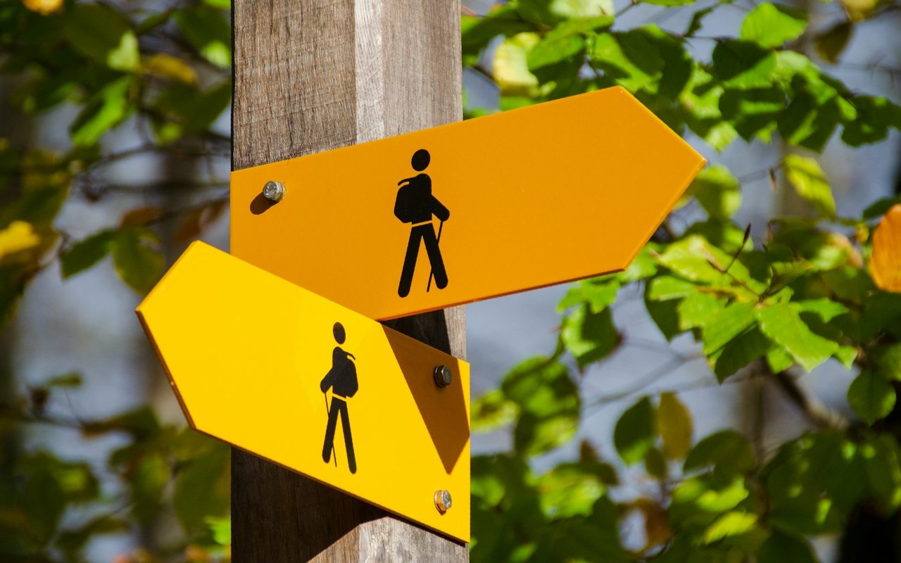 Opposing yellow directional signs with hiker symbols attached to a wooden post