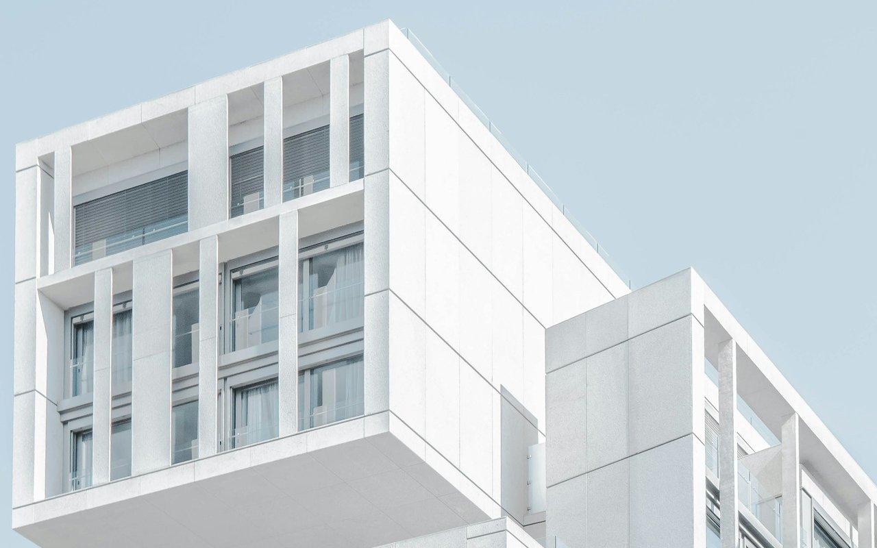 Modern white commercial building with large windows and glass balcony railings.