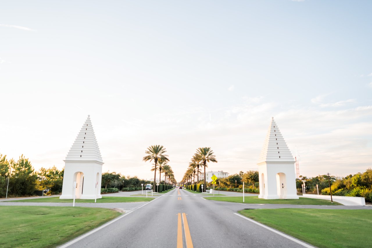 Twin white Bermuda-style entry towers along a palm-lined avenue at dusk in Alys Beach on 30A, Florida