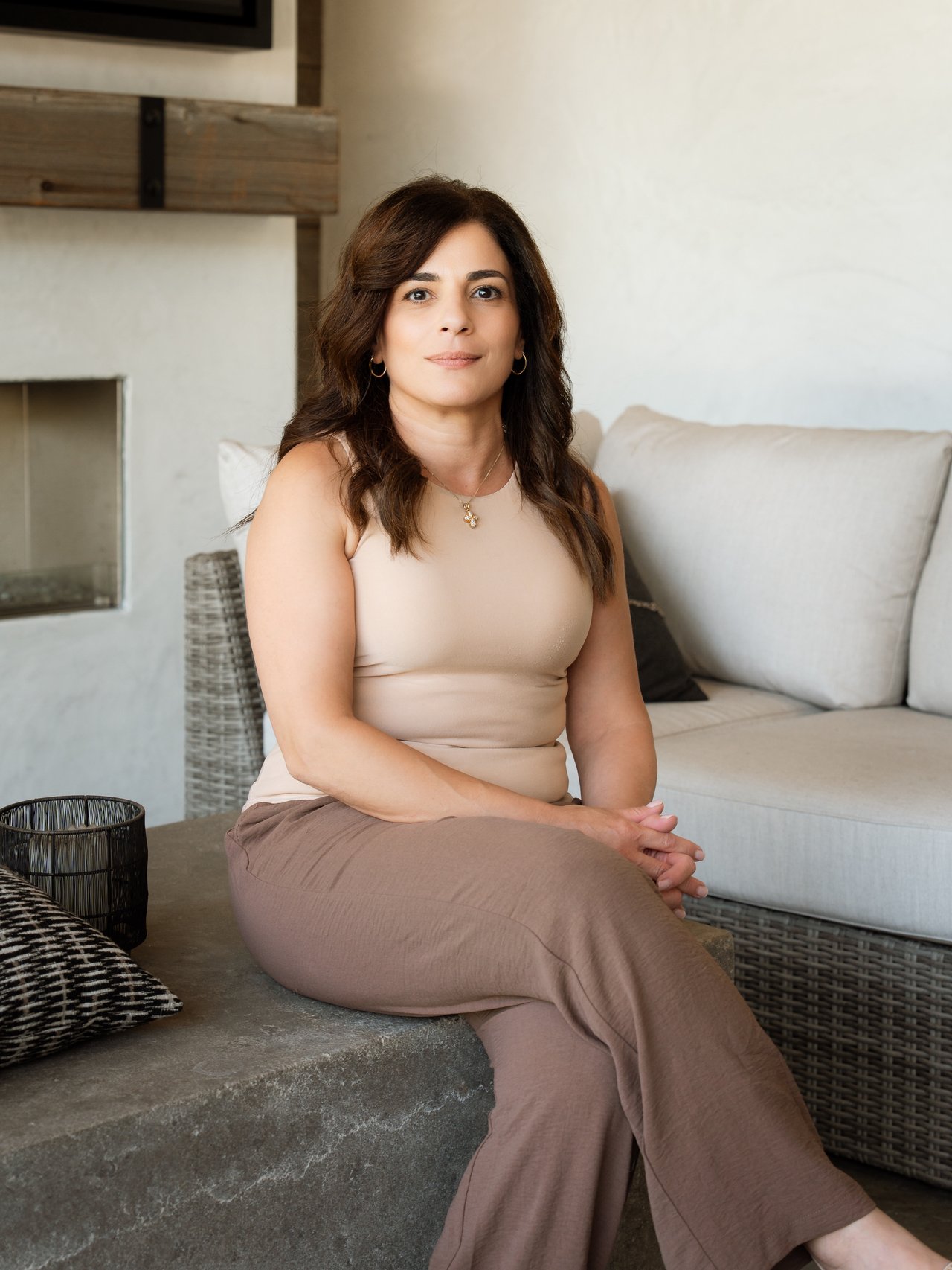 Nancy Mezied seated on a stone bench in a bright living room.