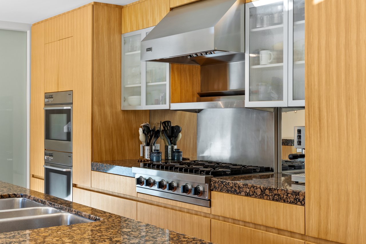 Modern kitchen with wood cabinetry, a stainless-steel range, and dark stone countertops.