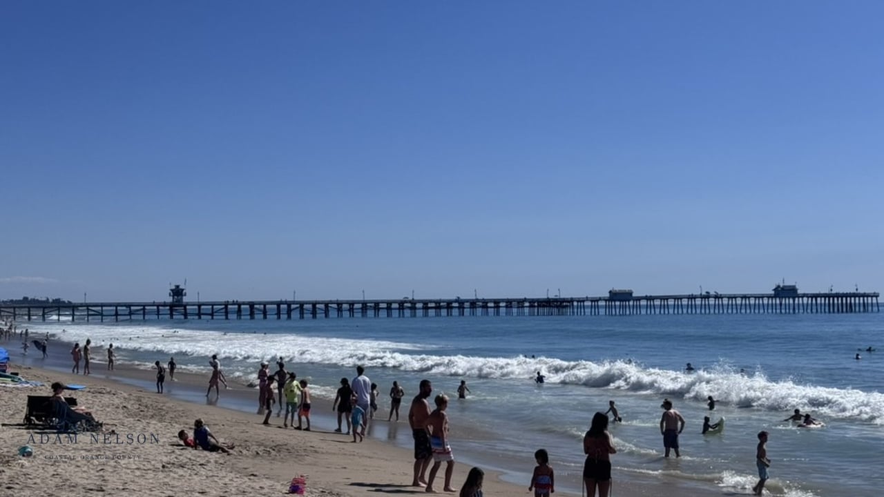 Beachgoers gather along the shore beneath San Clemente Pier.