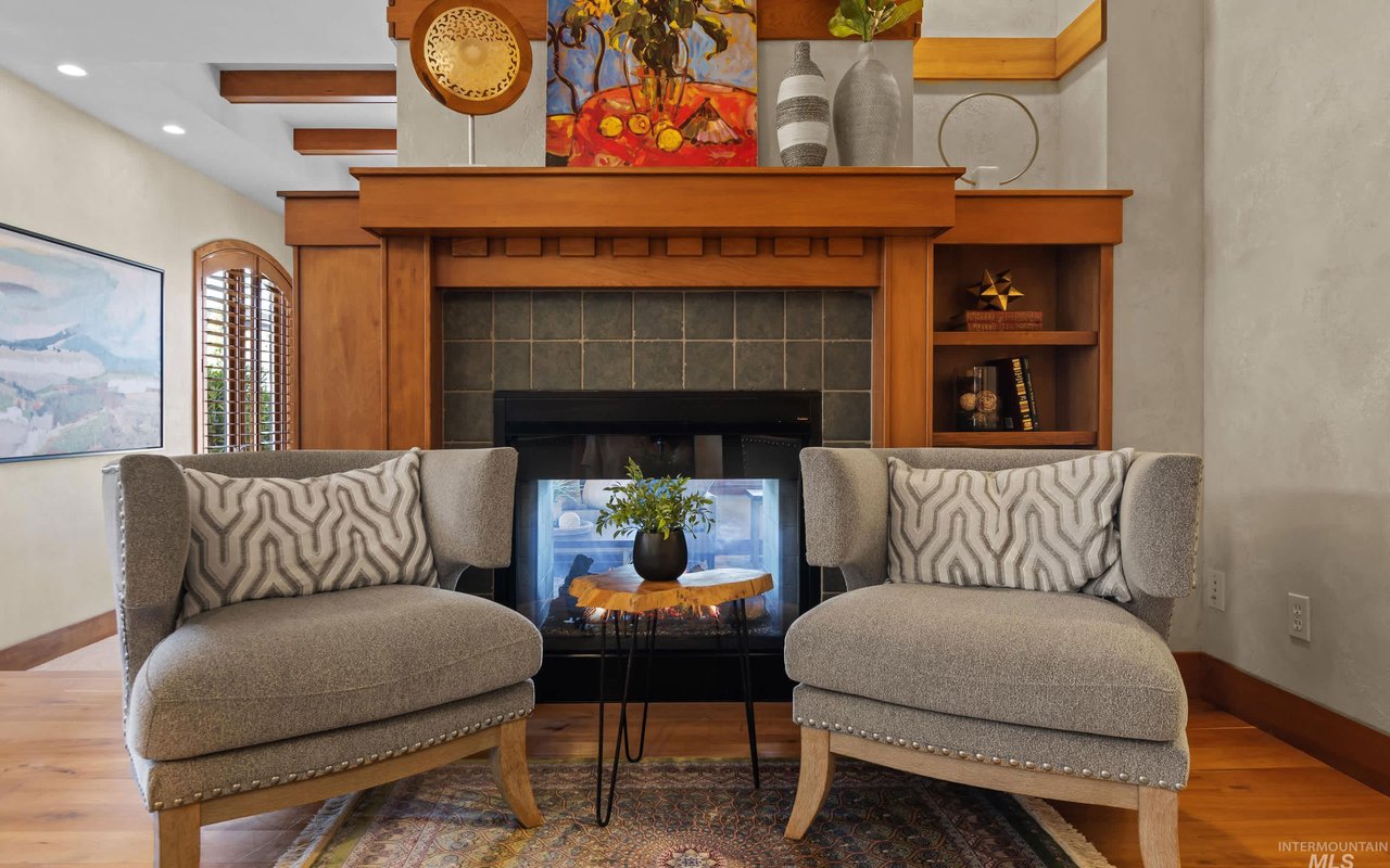 The sitting room features a double-sided fireplace tiled with rustic sage green tiles. The solid wood Arts and Crafts mantle flows into adjoining built-in shelves.