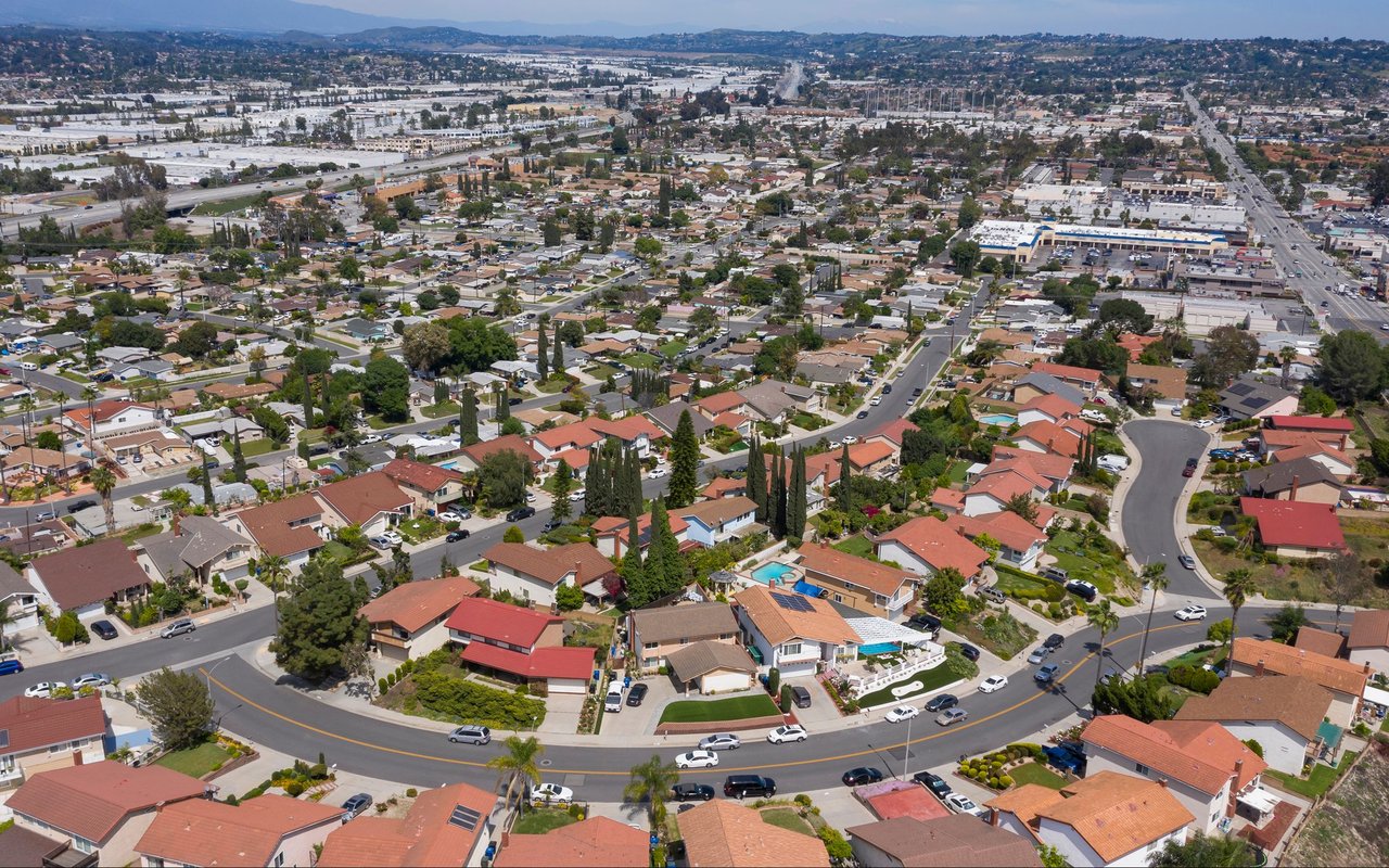 Aerial view of a suburban neighborhood with a curving street and mountains in the distance.