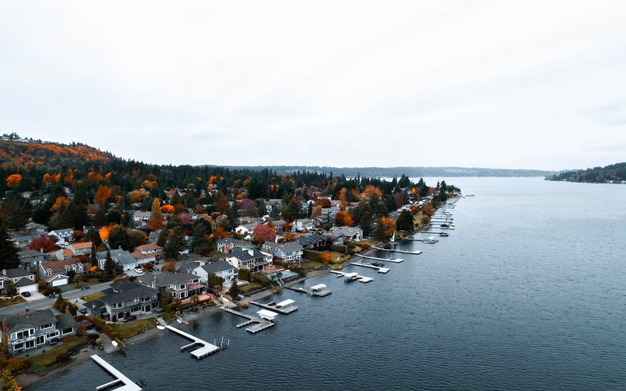 A quiet residential area with colorful houses lining a street next to a lake.