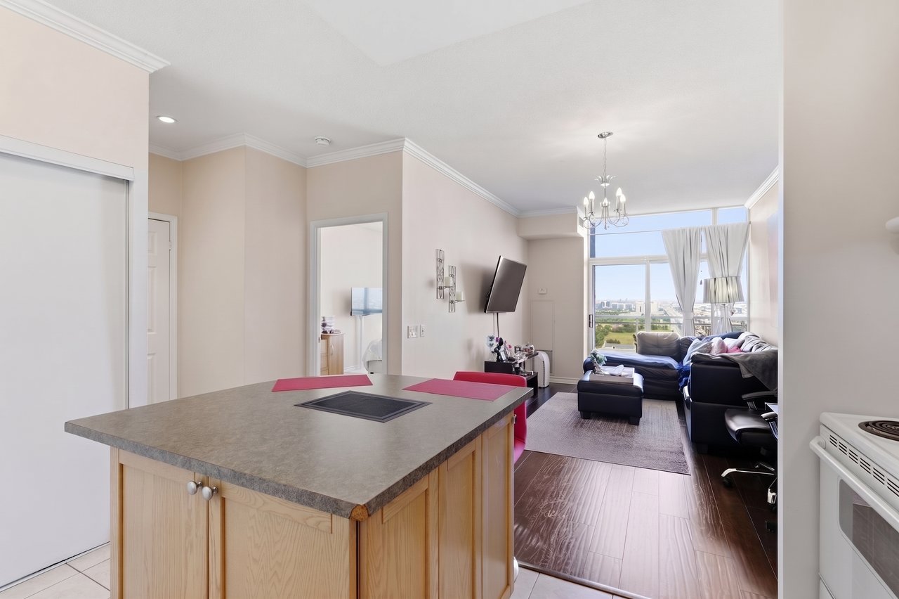 Open-plan condo kitchen and living room with a large island and windows overlooking the city.