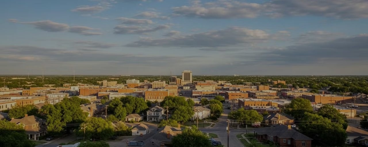 Aerial view of a small city, with low-rise downtown buildings and tree-lined neighborhoods.