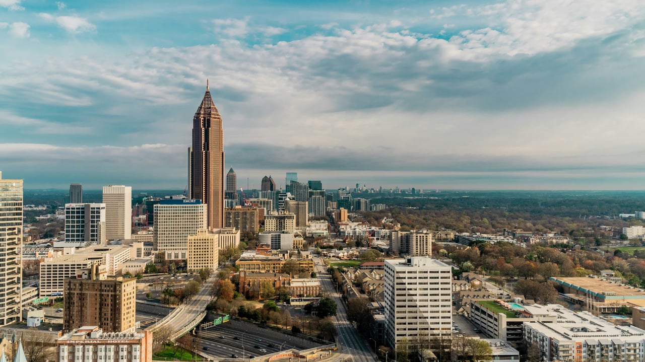 Aerial view of downtown Atlanta skyline surrounded by tree-filled neighborhoods