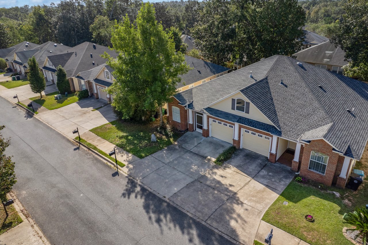 Aerial view of 5441 Hampton Hill Circle, Tallahassee, Florida 32311 showing brick townhome with two-car garage and landscaped yard.