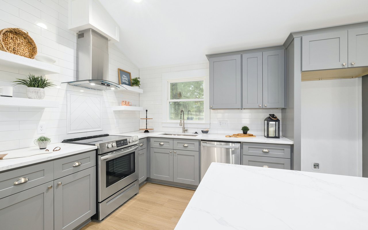 Bright kitchen with gray cabinets, stainless steel appliances, and a large white island.