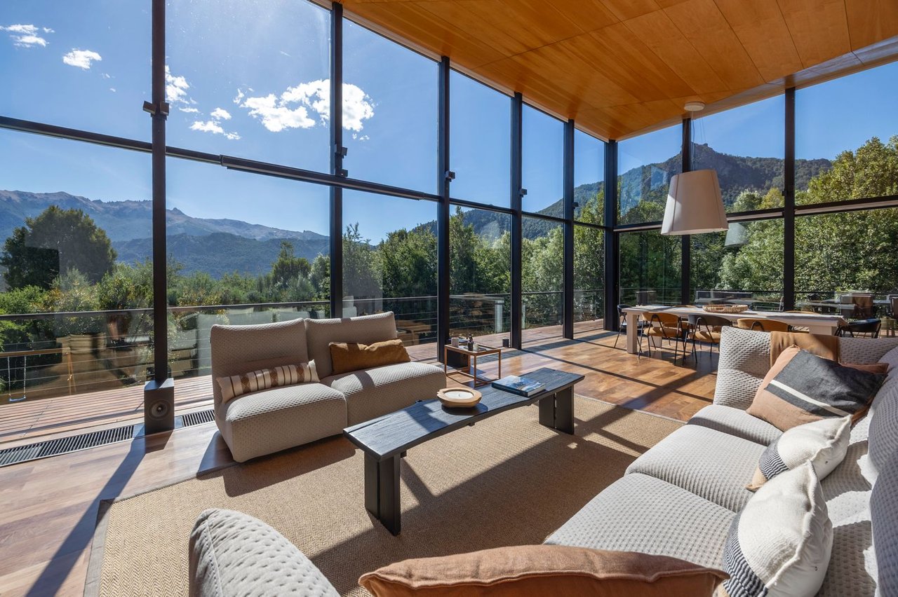 Modern living room with floor-to-ceiling windows overlooking forested mountains.