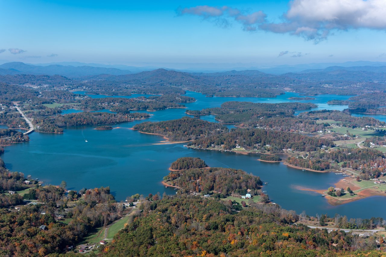 Aerial view of a winding mountain lake edged by autumn-colored hills and scattered homes.