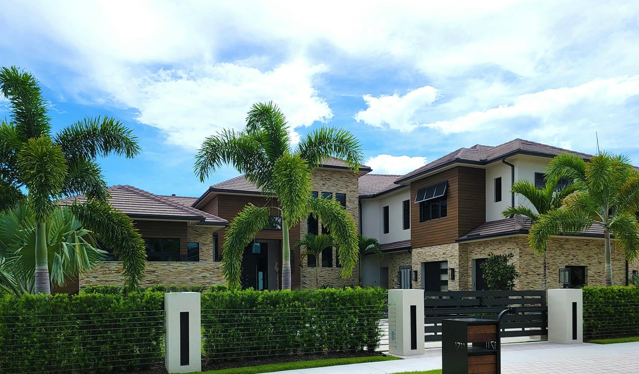 Modern luxury residential home with palm trees, stone facade, and landscaped front yard