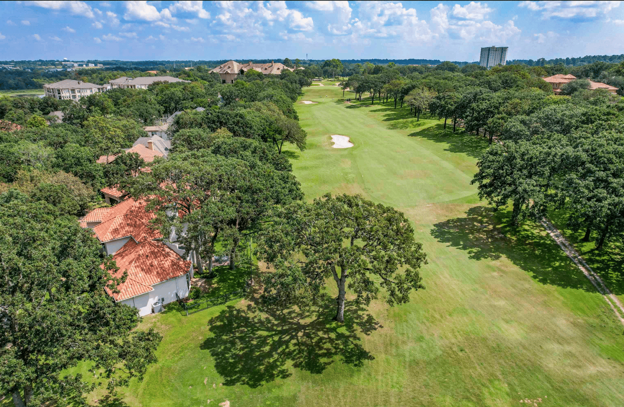 Aerial view of a luxury home with a terra cotta tile roof backing up to the golf course fairway in The Cascades neighborhood, Tyler, TX