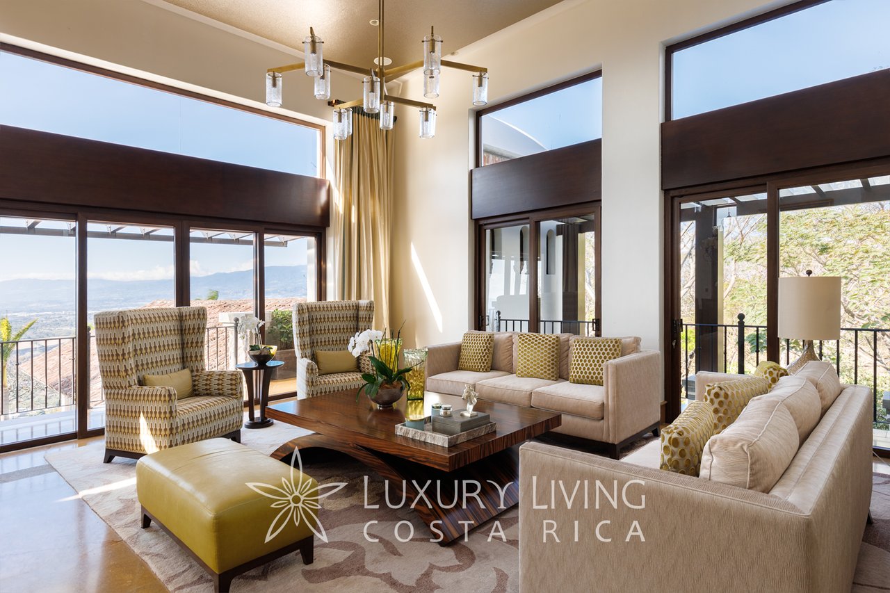 Furnished living room with expansive windows, mountain views, and a sculptural chandelier.